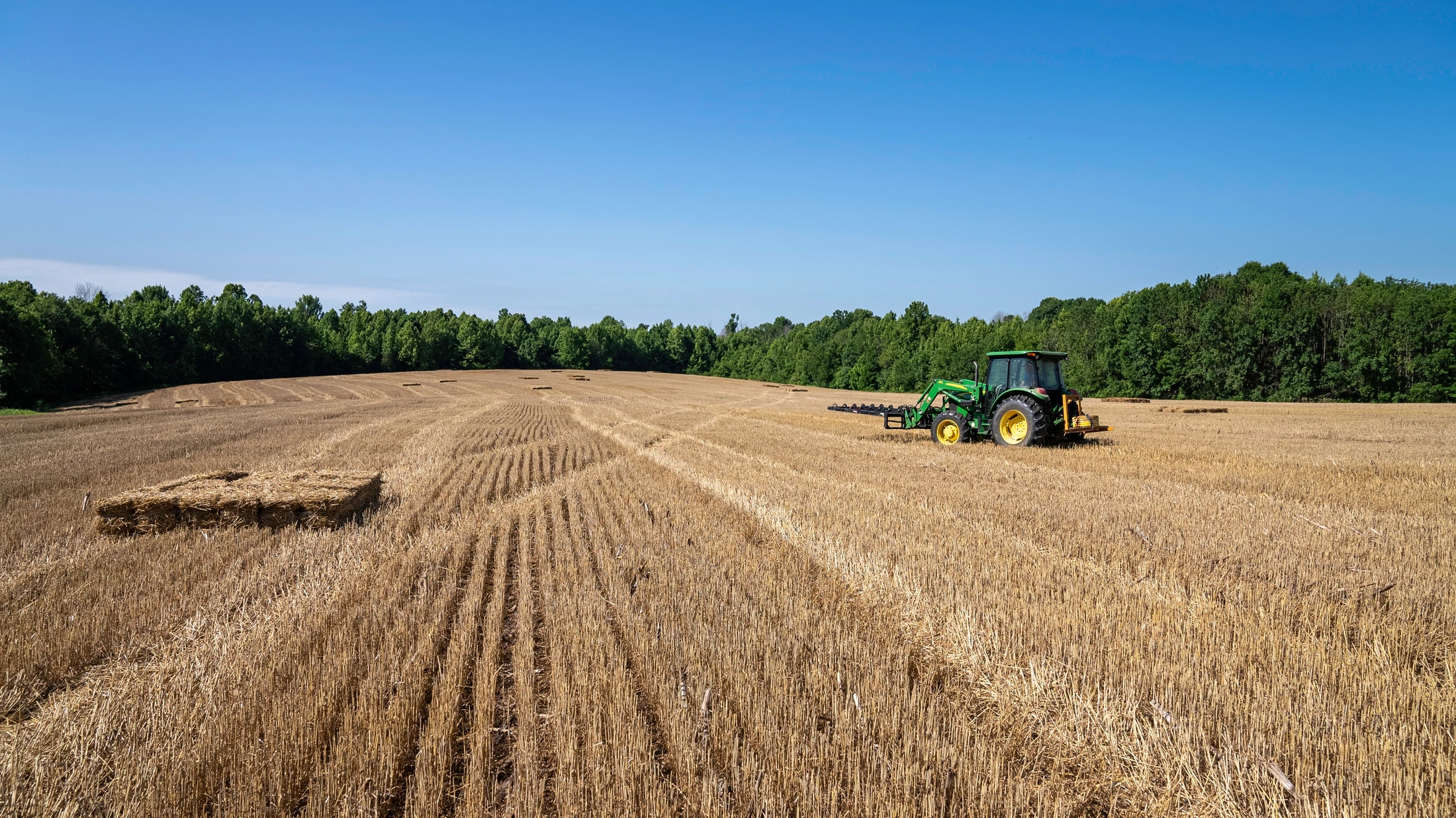 Campo cultivado com trator ao fundo, imagem ilustrativa de aplicação rural